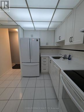 Mississauga (Cooksville) condo for rent - A white kitchen with a refrigerator, cabinets, and a sink.