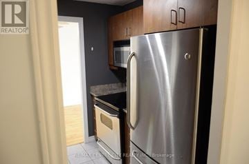 London South (South J) condo for rent - A stainless steel refrigerator is in a kitchen with wooden cabinets.