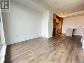 Toronto (Regent Park) condo for rent - A spacious room with wood flooring and a kitchenette in the corner.