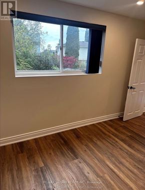 Waterloo apartment for rent - A room with a wooden floor and a window showing a view of trees and a house.