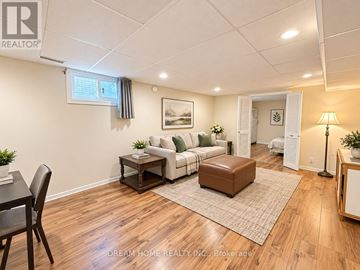 Toronto (L'amoreaux) apartment for rent - A well-lit living room with a brown rug and a brown ottoman.