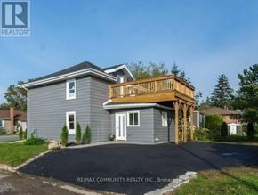 Quinte West (Trenton Ward) apartment for rent - A house with a grey exterior and a wooden deck.
