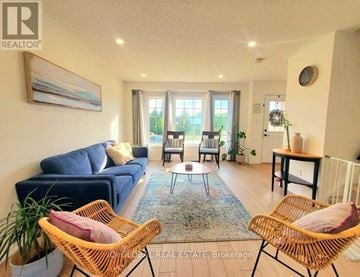 Guelph (Victoria North) townhouse for rent - A living room with a blue couch and two wicker chairs.