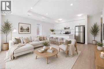 Kitchener townhouse for rent - A modern living room with a white sofa, wooden coffee table, and a kitchen in the background.