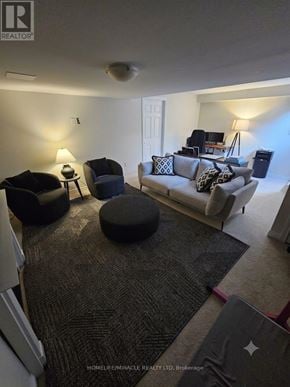 Oakville (Bc Bronte Creek) townhouse for rent - A living room with a grey couch and a black ottoman.