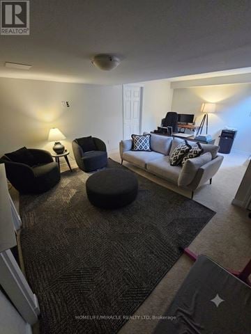 Oakville (Bc Bronte Creek) townhouse for rent - A living room with a grey couch and a black ottoman.