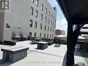 Oshawa (Central) condo for rent - A rooftop patio with tables and chairs overlooks a cityscape.
