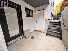 Burnaby apartment for rent - A concrete patio area with a door and steps leading to a building.