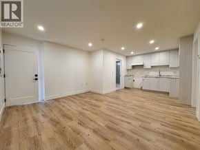Burnaby apartment for rent - A spacious room with wooden flooring and white walls.