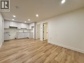 Burnaby apartment for rent - A spacious kitchen and living room with wooden flooring and white walls.