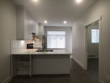Surrey townhouse for rent - A kitchen with white cabinets and a window with blinds.