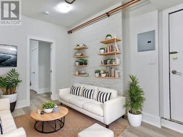 Toronto (Wychwood) multi-family for rent - A living room with a white couch, a coffee table, and a plant.