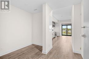 Welland (Broadway) condo for rent - A spacious room with white walls and wooden flooring, leading to a balcony with a view of the outdoors.