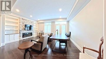 Waterloo townhouse for rent - A well-lit living room with a brick fireplace and a dining table set for four.