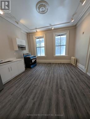 London East (East K) multi-family for rent - A room with wooden flooring and a window with white curtains.