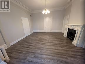 London East (East K) multi-family for rent - A large, empty room with a fireplace and wood flooring.
