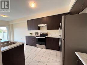 Bradford West Gwillimbury (Bradford) townhouse for rent - A kitchen with brown cabinets and a white fridge.