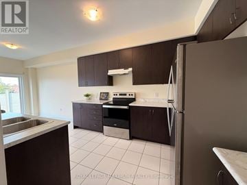 Bradford West Gwillimbury (Bradford) townhouse for rent - A kitchen with brown cabinets and a white fridge.