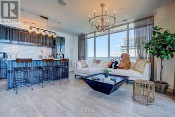 Toronto (Mimico) condo for rent - A woman is sitting on a couch in a bright living room with a bar area.