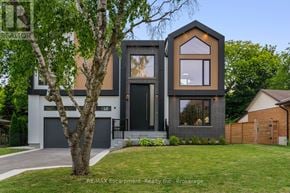 Burlington (Shoreacres) apartment for rent - A modern house with a black and beige exterior and a large front yard.