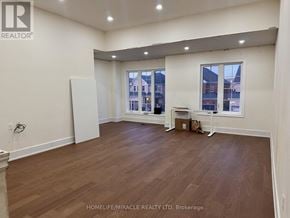 Whitby (Williamsburg) apartment for rent - A room with wooden flooring and white walls, with a window showing a view of buildings outside.