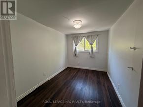 Niagara Falls (Ascot) apartment for rent - A room with wooden floors and white walls, with a window covered by a white curtain.