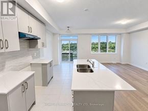 Haldimand townhouse for rent - A kitchen with white cabinets and a large island with a sink.