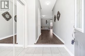 Brampton (Bram East) apartment for rent - A hallway with a white door and a white wall with a mirror and a picture on it.