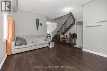 Brampton (Bram East) apartment for rent - A living room with a white couch and a wooden staircase.
