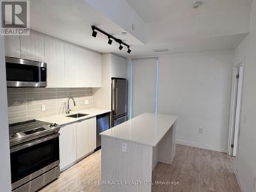 Toronto (Birchcliffe-Cliffside) townhouse for rent - A kitchen with a stove top oven, microwave, and refrigerator.
