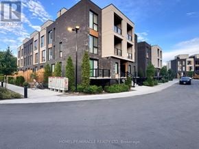 Toronto (Birchcliffe-Cliffside) townhouse for rent - A street view of a residential area with apartment buildings and a car driving on the road.