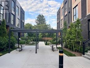 Toronto (Birchcliffe-Cliffside) townhouse for rent - A walkway with benches and a canopy leads to a building.