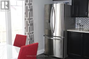Collingwood duplex for rent - A kitchen with a stainless steel refrigerator, red chairs, and black cabinets.