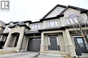Hamilton townhouse for rent - A large, two-story house with a stone facade and a black garage door.