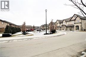 Hamilton townhouse for rent - A street view of a residential area with houses on both sides and a parked car on the left.