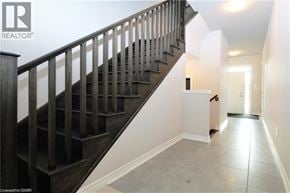 Hamilton townhouse for rent - A wooden staircase with a metal railing leads up to a white wall.