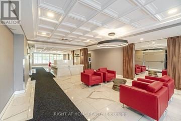 Mississauga (Cooksville) condo for rent - A spacious living room with red furniture and a black carpet.