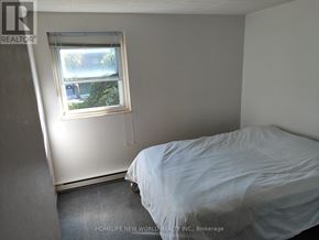 Windsor condo for rent - A bedroom with a bed and a window overlooking a street.