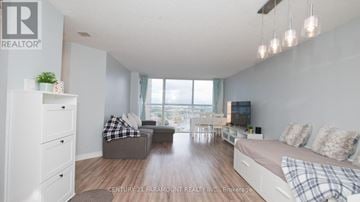 Mississauga (Hurontario) condo for rent - A well-lit, spacious living room with a grey sofa and a white couch.