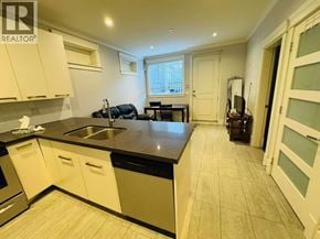 Vancouver apartment for rent - A kitchen with white cabinets and black countertops.