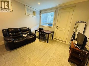 Vancouver apartment for rent - A living room with a black leather sofa and a wooden coffee table.