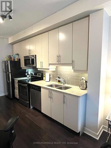 Toronto (Waterfront Communities) condo for rent - A kitchen with white cabinets and black appliances.