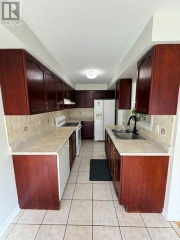 Mississauga (Meadowvale Village) townhouse for rent - A kitchen with brown cabinets and a white fridge.