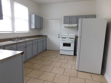 New Orleans apartment for rent - A kitchen with a refrigerator, sink, and cabinets.