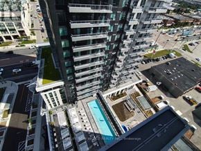 Vaughan (Vaughan Corporate Centre) condo for rent - A tall building with a pool in the middle of a parking lot.