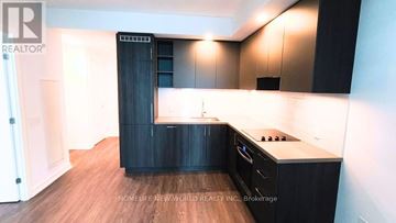 Vaughan (Vaughan Corporate Centre) condo for rent - A modern kitchen with dark wood cabinets and a white countertop.