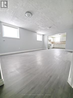 Barrie (Georgian Drive) apartment for rent - A spacious room with wooden flooring and white walls.