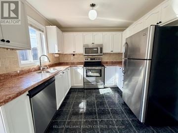 Barrie (400 West) apartment for rent - A kitchen with a black fridge and white cabinets.
