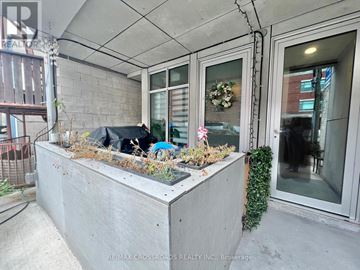 Toronto (Junction Area) multi-family for rent - A concrete planter box with plants and a black umbrella on a patio.