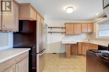 Barrie (Codrington) triplex for rent - A kitchen with wooden cabinets and a black refrigerator.